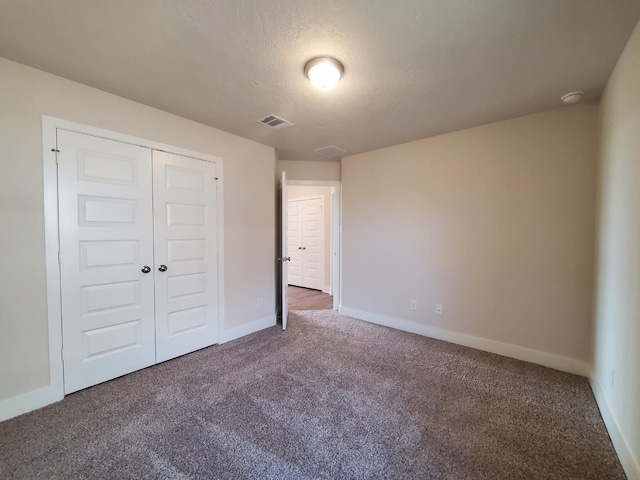 unfurnished bedroom featuring carpet, visible vents, baseboards, a closet, and a textured ceiling