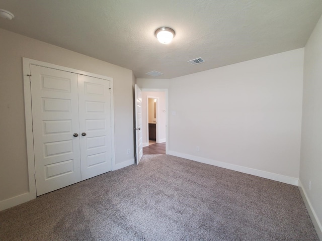 unfurnished bedroom with baseboards, visible vents, carpet floors, and a closet