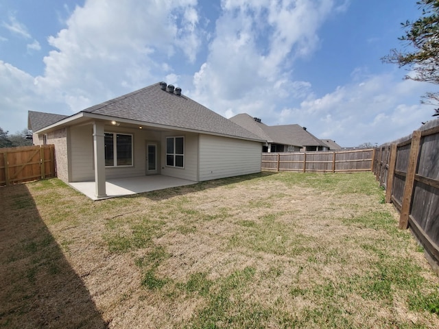 back of property with roof with shingles, a yard, a fenced backyard, a patio area, and brick siding