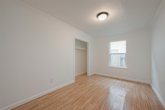 unfurnished bedroom featuring a textured ceiling, a closet, light wood-type flooring, and ornamental molding