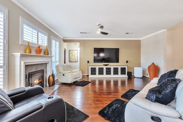 living room featuring hardwood / wood-style floors, ceiling fan, a tile fireplace, and crown molding