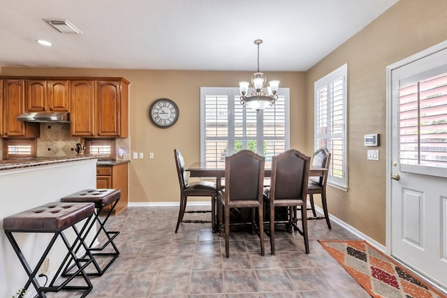 dining space with a chandelier, a wealth of natural light, and light tile patterned floors