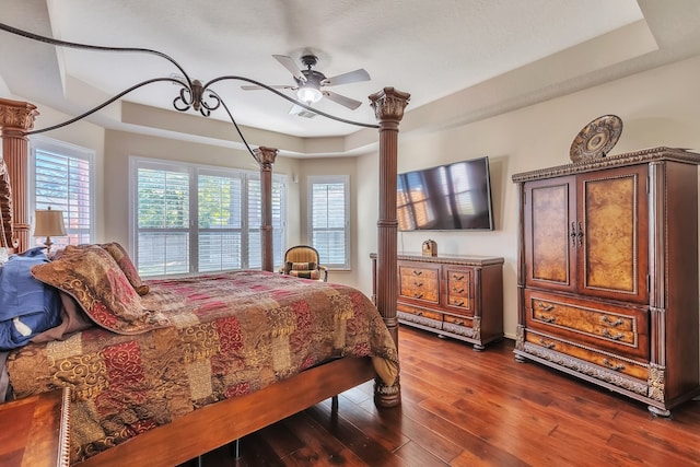 bedroom with ceiling fan, dark hardwood / wood-style floors, and a raised ceiling