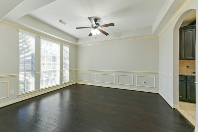 spare room featuring ornamental molding, dark wood-type flooring, ceiling fan, and a tray ceiling