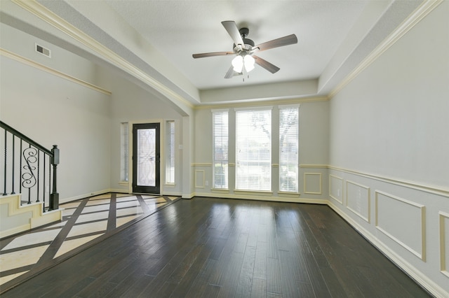 interior space with dark hardwood / wood-style flooring, ceiling fan, crown molding, and a tray ceiling