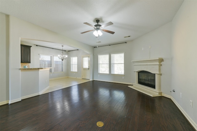 unfurnished living room featuring a textured ceiling, hardwood / wood-style floors, and ceiling fan with notable chandelier