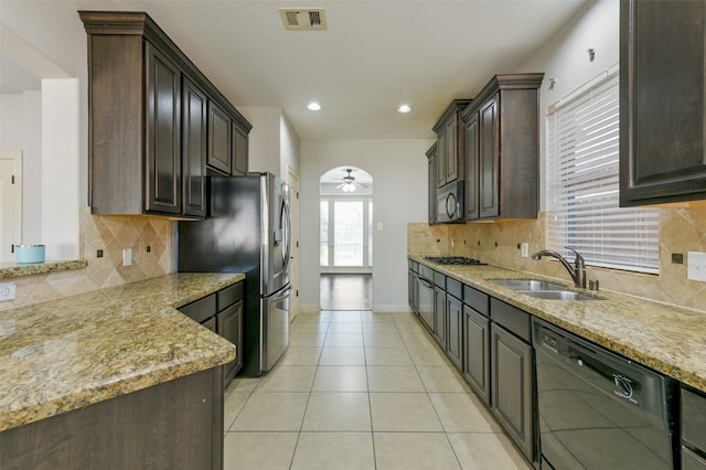 kitchen featuring tasteful backsplash, stainless steel appliances, light stone countertops, sink, and ceiling fan