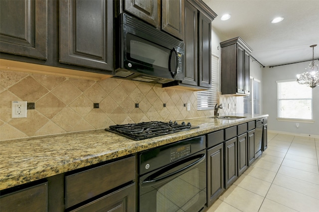 kitchen with black appliances, dark brown cabinets, pendant lighting, light stone countertops, and a chandelier