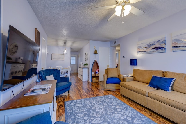 living room with ceiling fan, a textured ceiling, and dark hardwood / wood-style floors