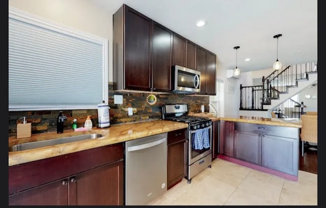 kitchen featuring stainless steel appliances, backsplash, decorative light fixtures, light tile patterned floors, and sink