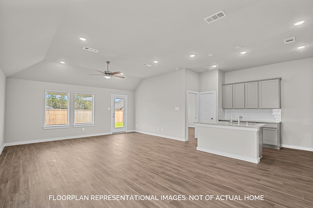 unfurnished living room featuring hardwood / wood-style flooring, ceiling fan, and vaulted ceiling