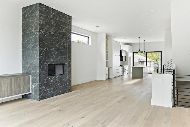 living room featuring a tile fireplace, radiator heating unit, light hardwood / wood-style floors, and tile walls