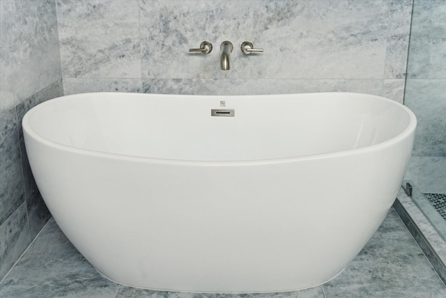 bathroom featuring tile patterned floors, tile walls, and a tub