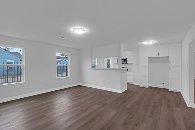 unfurnished living room featuring dark wood-type flooring and a wealth of natural light