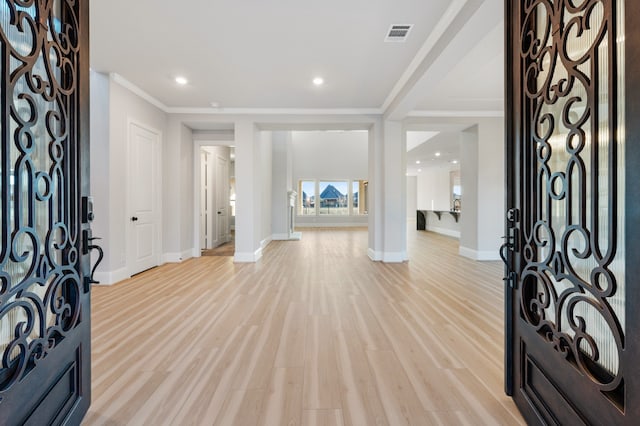 entryway with light hardwood / wood-style floors and ornamental molding