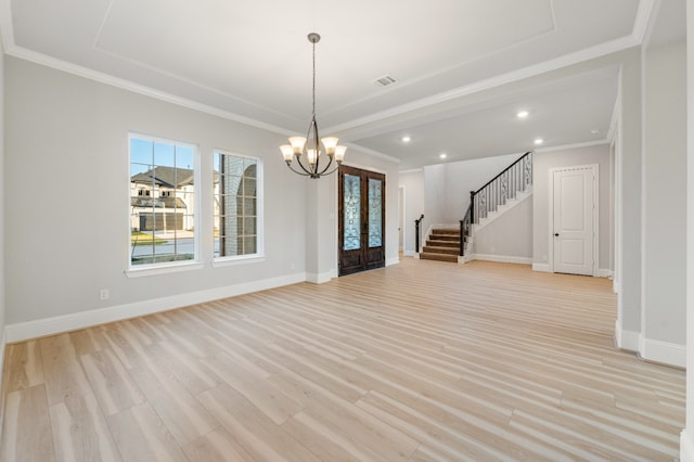 empty room with french doors, an inviting chandelier, ornamental molding, and light wood-type flooring