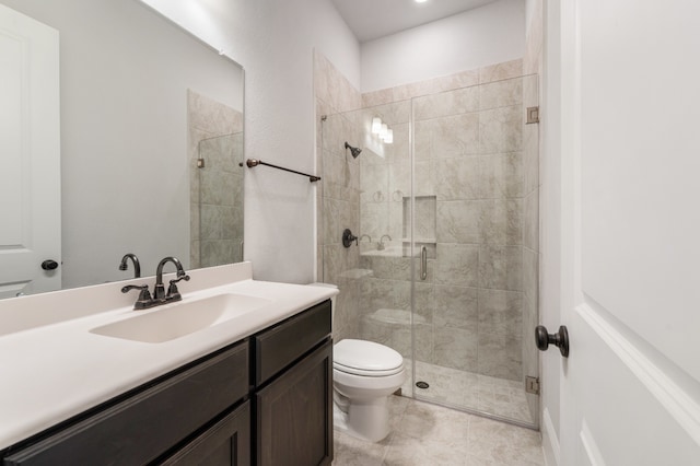 bathroom featuring tile patterned floors, vanity, toilet, and a shower with door