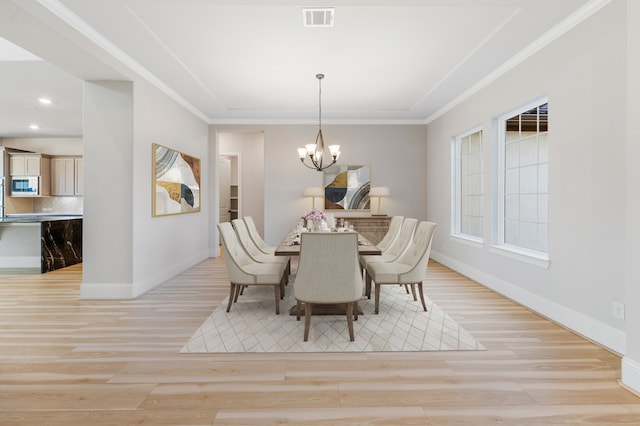 dining area featuring light wood-type flooring, crown molding, and a chandelier