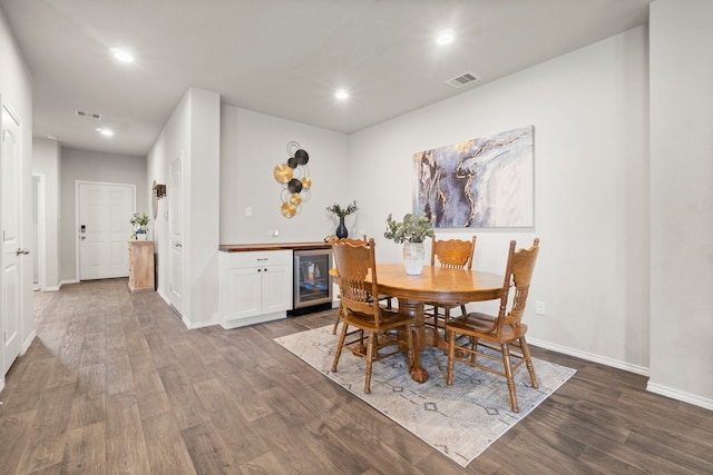 dining area featuring dark hardwood / wood-style flooring, wine cooler, and bar area