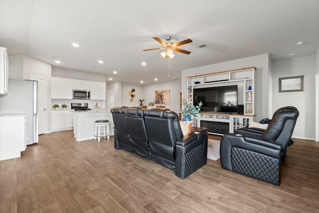 living room featuring a fireplace, light hardwood / wood-style floors, and ceiling fan