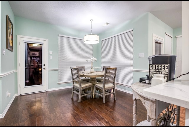 dining room featuring dark hardwood / wood-style flooring and a textured ceiling