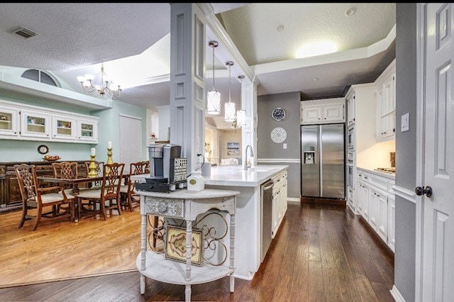 kitchen with hanging light fixtures, a textured ceiling, dark hardwood / wood-style floors, white cabinetry, and appliances with stainless steel finishes