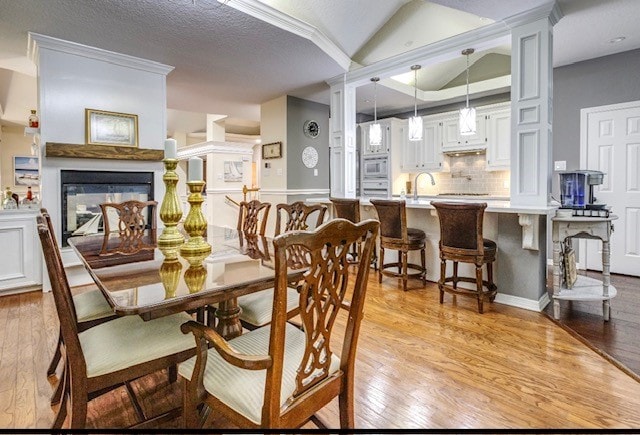 dining space featuring light hardwood / wood-style floors, lofted ceiling, and a textured ceiling