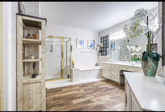 bathroom featuring plus walk in shower, vanity, a textured ceiling, and hardwood / wood-style flooring