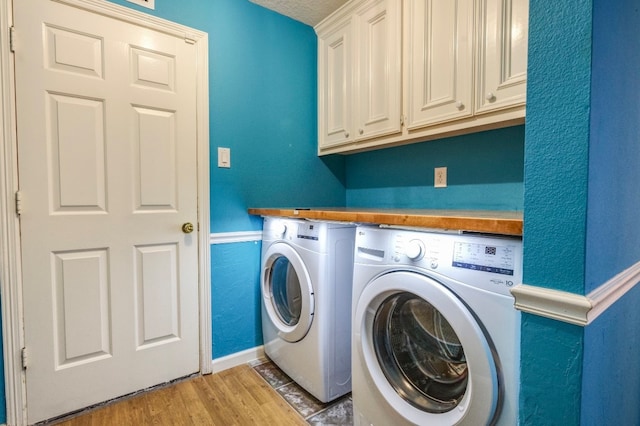 washroom featuring cabinets, a textured ceiling, wood-type flooring, and washer and clothes dryer