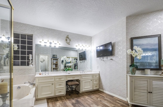 bathroom with a textured ceiling, a bathtub, vanity, and hardwood / wood-style flooring