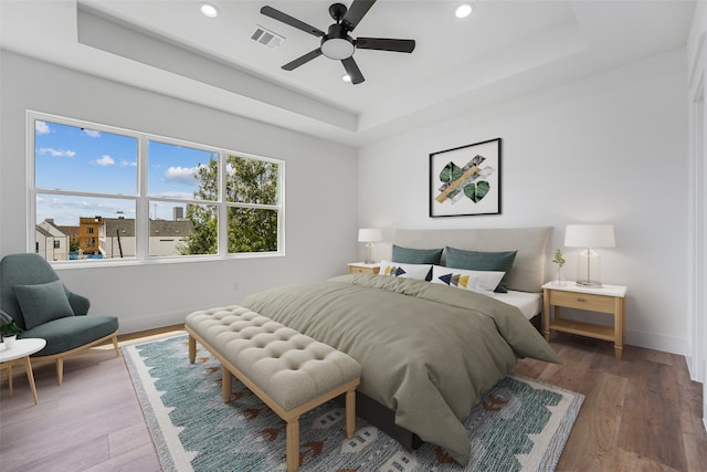 bedroom with a tray ceiling, ceiling fan, and hardwood / wood-style flooring