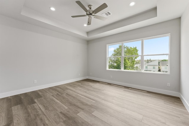 unfurnished room featuring light hardwood / wood-style floors, a raised ceiling, and ceiling fan