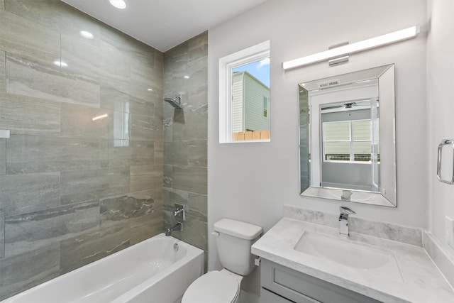 full bathroom featuring vanity, tiled shower / bath combo, and toilet