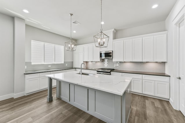 kitchen with a kitchen island with sink, white cabinetry, and stainless steel appliances