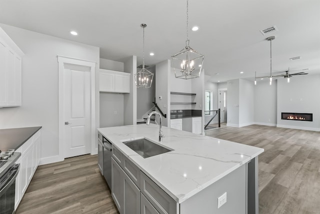 kitchen featuring light stone countertops, sink, a spacious island, decorative light fixtures, and white cabinets