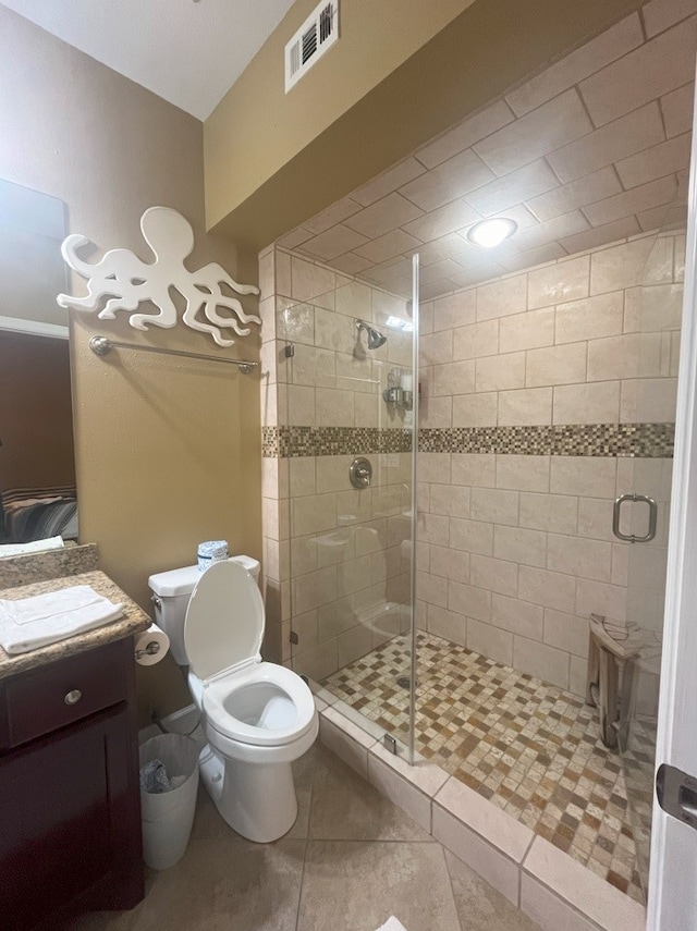 bathroom featuring toilet, vanity, tile patterned flooring, and a shower with shower door