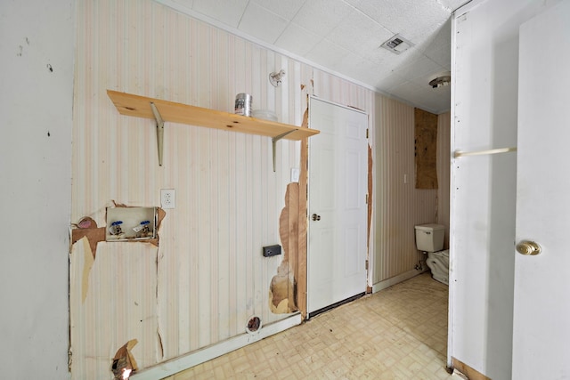 bathroom featuring wood walls and toilet