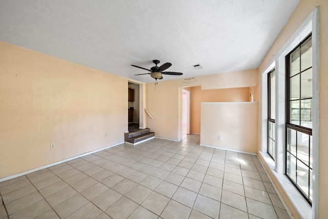 tiled empty room with a textured ceiling and ceiling fan