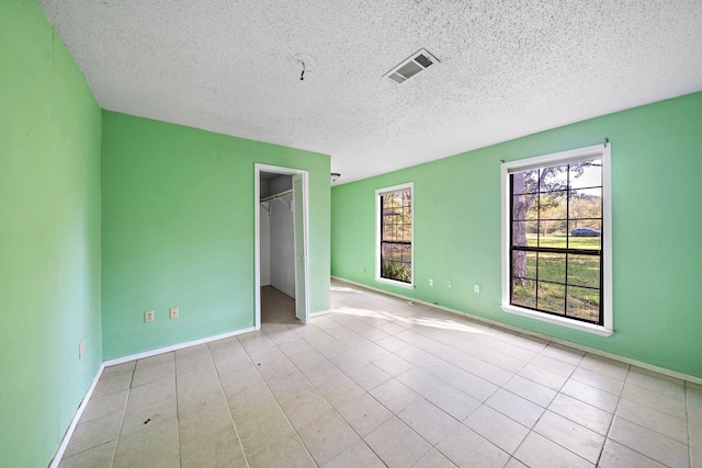 unfurnished bedroom featuring a textured ceiling, a closet, and a spacious closet