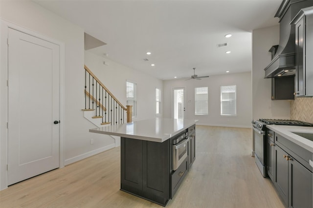 kitchen with a center island, ceiling fan, decorative backsplash, light hardwood / wood-style floors, and stainless steel appliances