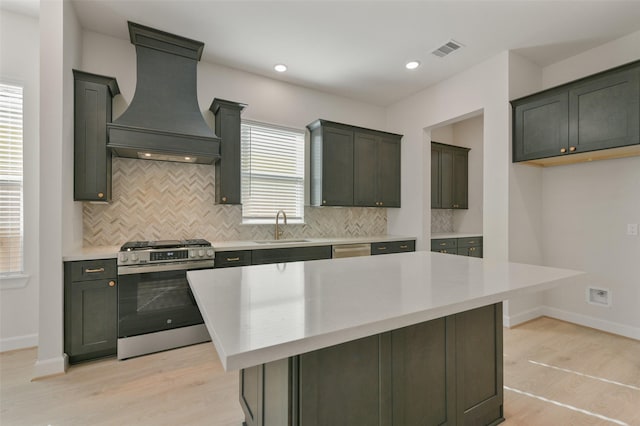 kitchen featuring a center island, sink, light hardwood / wood-style flooring, custom range hood, and stainless steel appliances