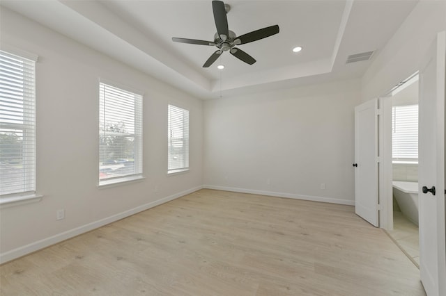 spare room featuring ceiling fan, a raised ceiling, and light wood-type flooring