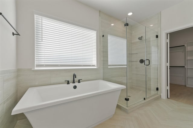 bathroom with shower with separate bathtub and tile walls