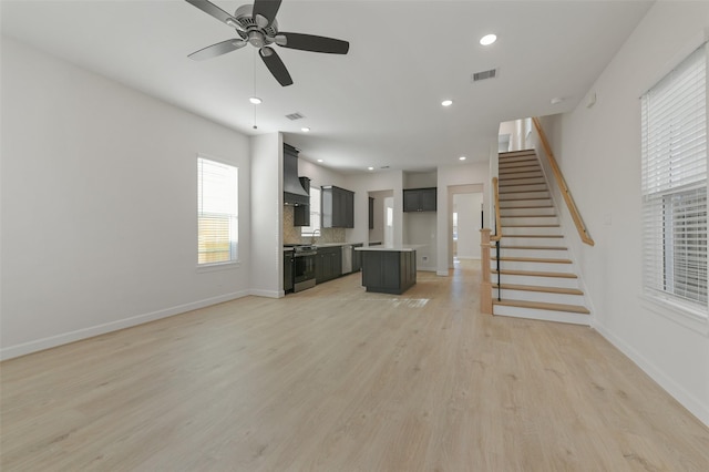 unfurnished living room featuring ceiling fan and light wood-type flooring