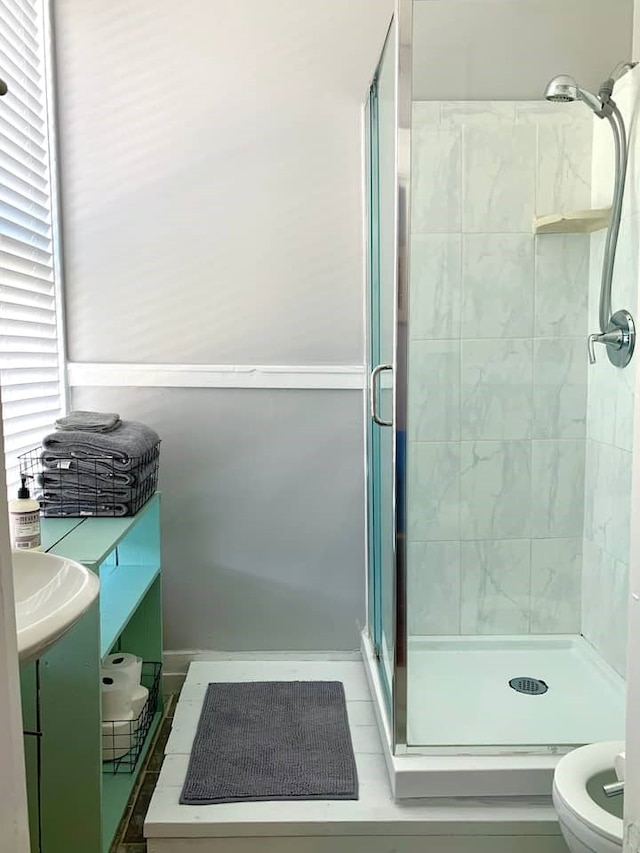 bathroom featuring a shower with door, vanity, and toilet