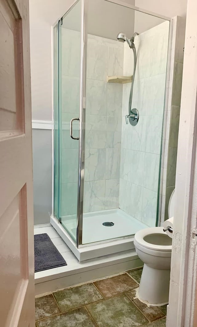 bathroom with toilet and a shower with shower door