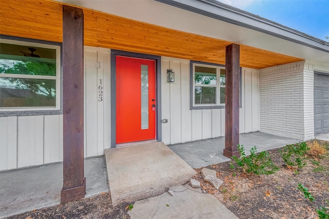 doorway to property featuring a porch and brick siding