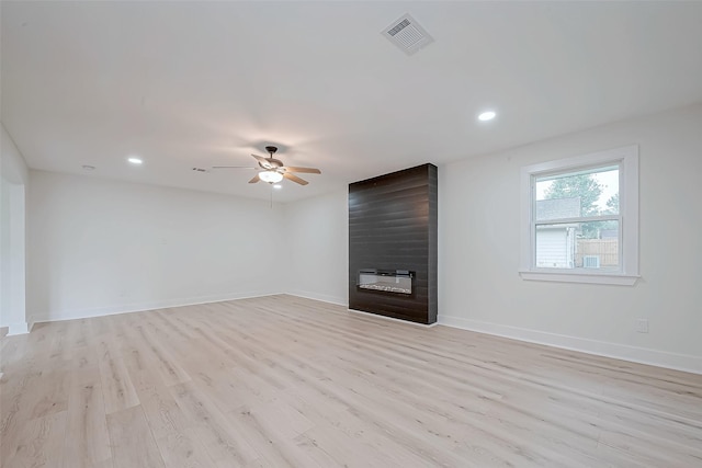 unfurnished living room with ceiling fan, a large fireplace, light wood finished floors, baseboards, and recessed lighting