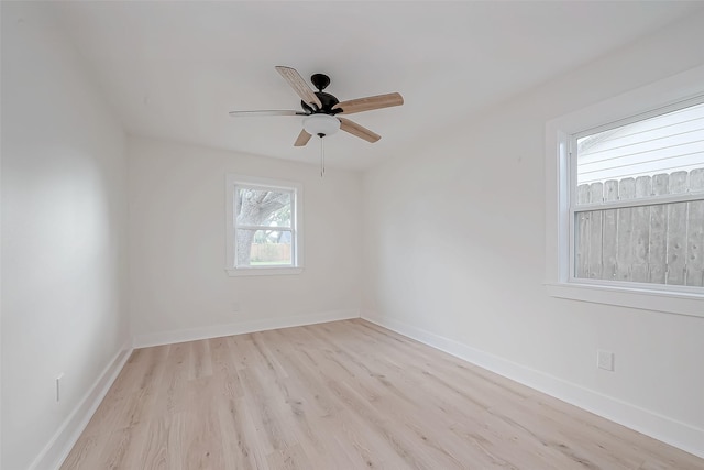 spare room featuring light wood-type flooring, a ceiling fan, and baseboards
