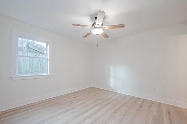 spare room with light wood-type flooring, a ceiling fan, and baseboards